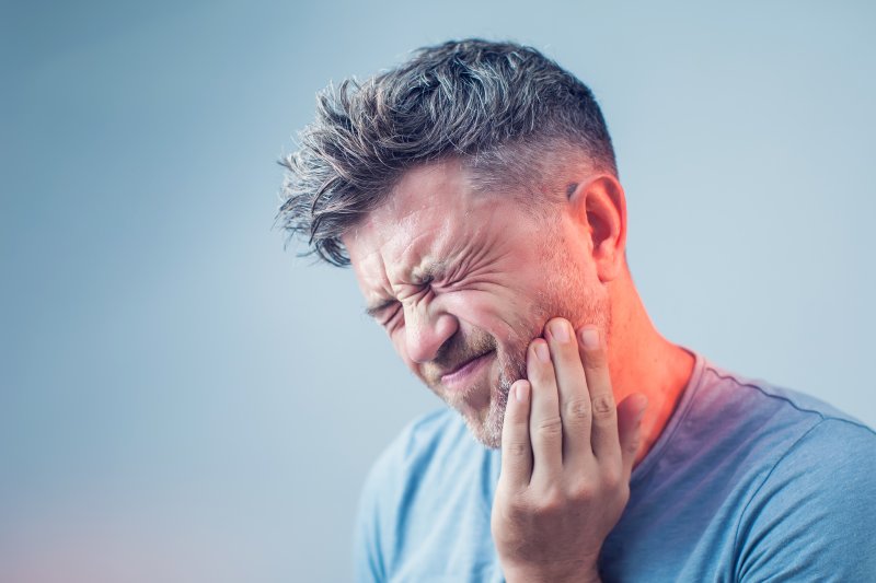 person having dental emergency holding cheek 